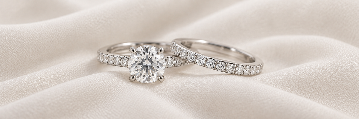 Matching bridal set with round diamond engagement ring and diamond band on matte ivory fabric