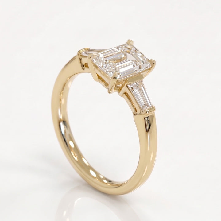 Side profile of an emerald-cut three-stone natural diamond ring in 14K yellow gold