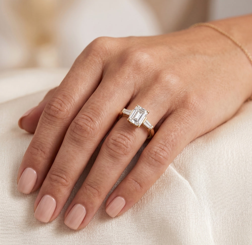 Emerald-cut three-stone natural diamond engagement ring worn on hand